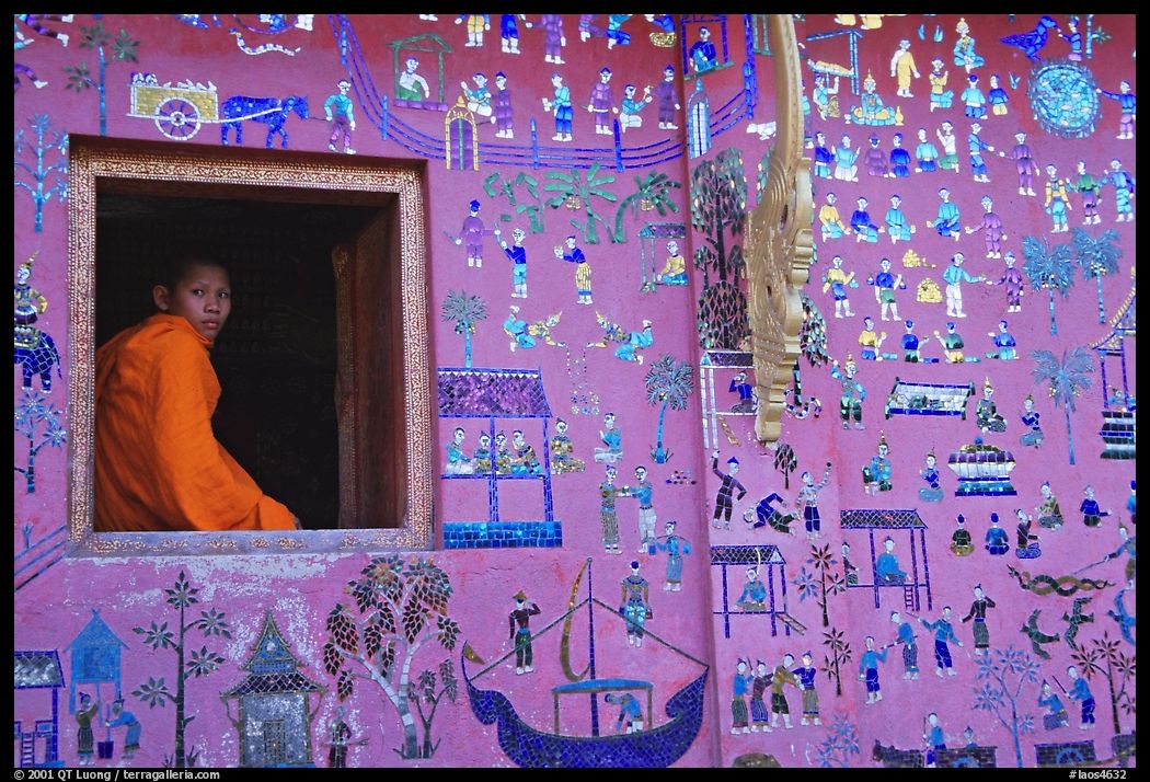 Buddhist novice monk sits at the window of a shrine, Wat Xieng Thong. Luang Prabang, Laos