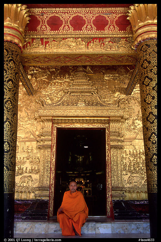 Buddhist novice monk sits at the door of the Wat Mai Suwannaphumaham. Luang Prabang, Laos