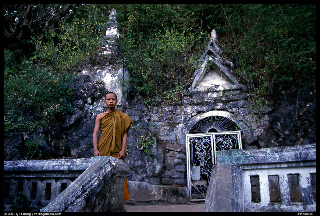 Novice Buddhist monk at entrance of cave. Laos