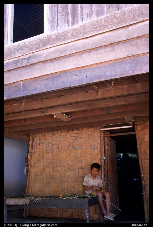 Boy at the entrance of traditional hut, Ban Xang Hai. Laos