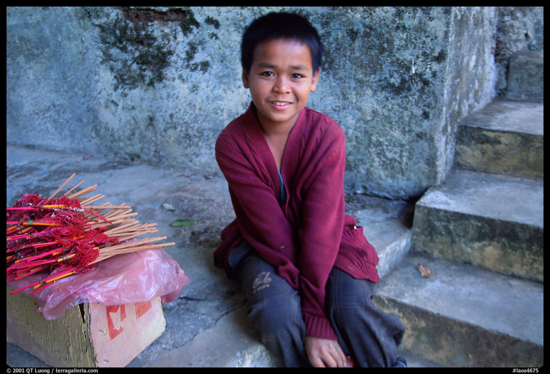 Boy sells incence sticks at the entrance of a shrine, Pak Ou. Laos