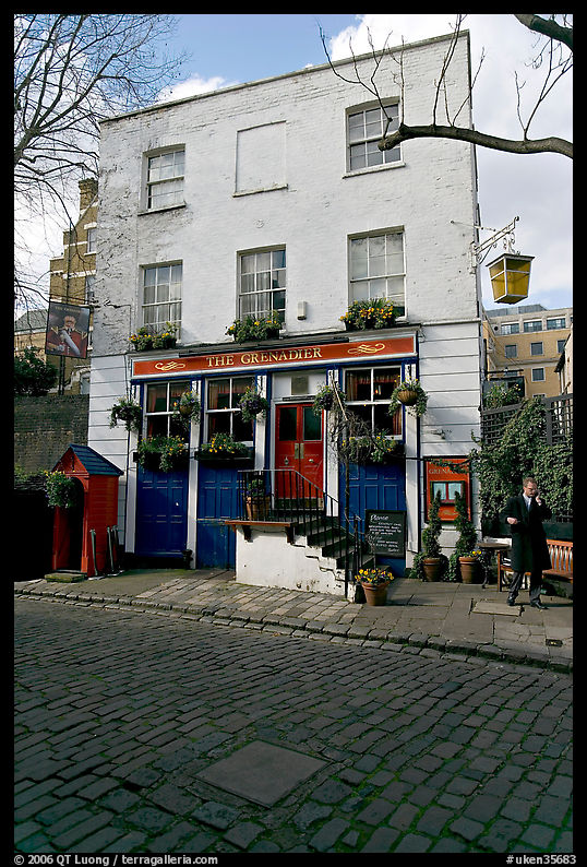 Cobblestone mews, pub, and man standing outside. London, England, United Kingdom