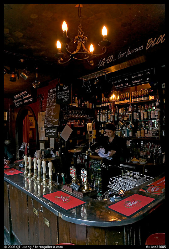Woman cleaning glass at the bar, pub The Grenadier. London, England, United Kingdom