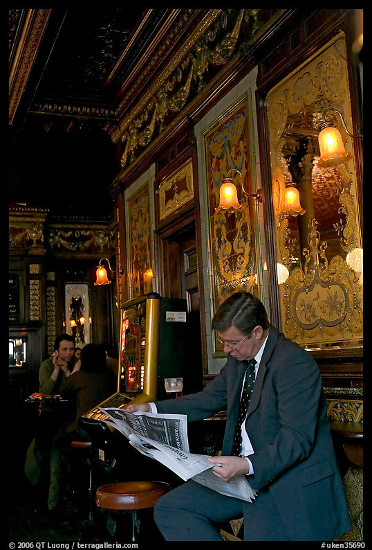 Man reading newspaper in front of etched mirrors, pub Princess Louise. London, England, United Kingdom