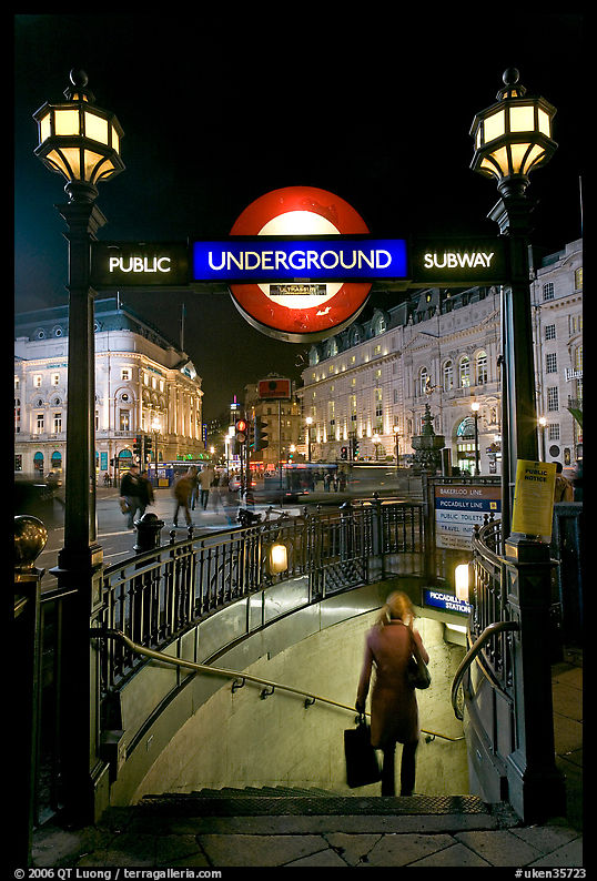Woman with shopping bag entering subway at night, Piccadilly Circus. London, England, United Kingdom
