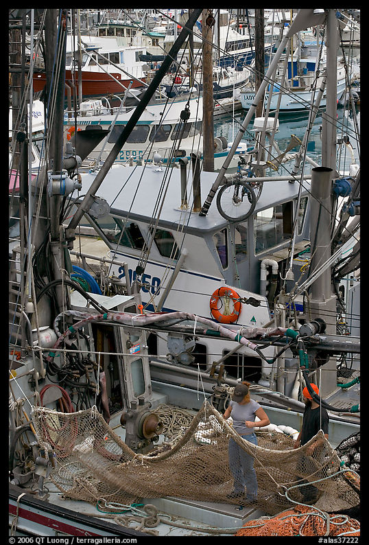 Man and woman repairing nets on fishing boat. Whittier, Alaska, USA