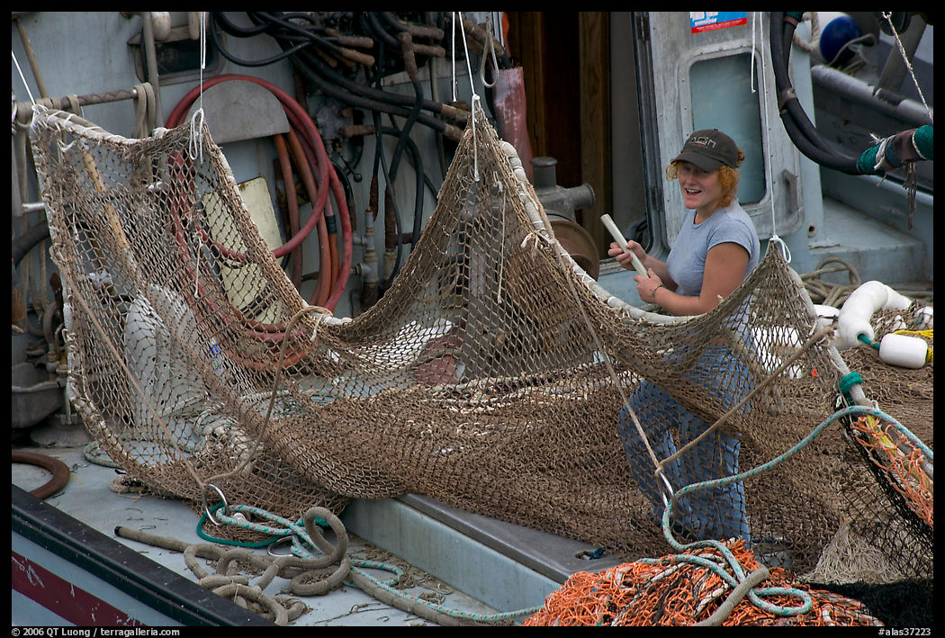 Woman repairing net on fishing boat. Whittier, Alaska, USA