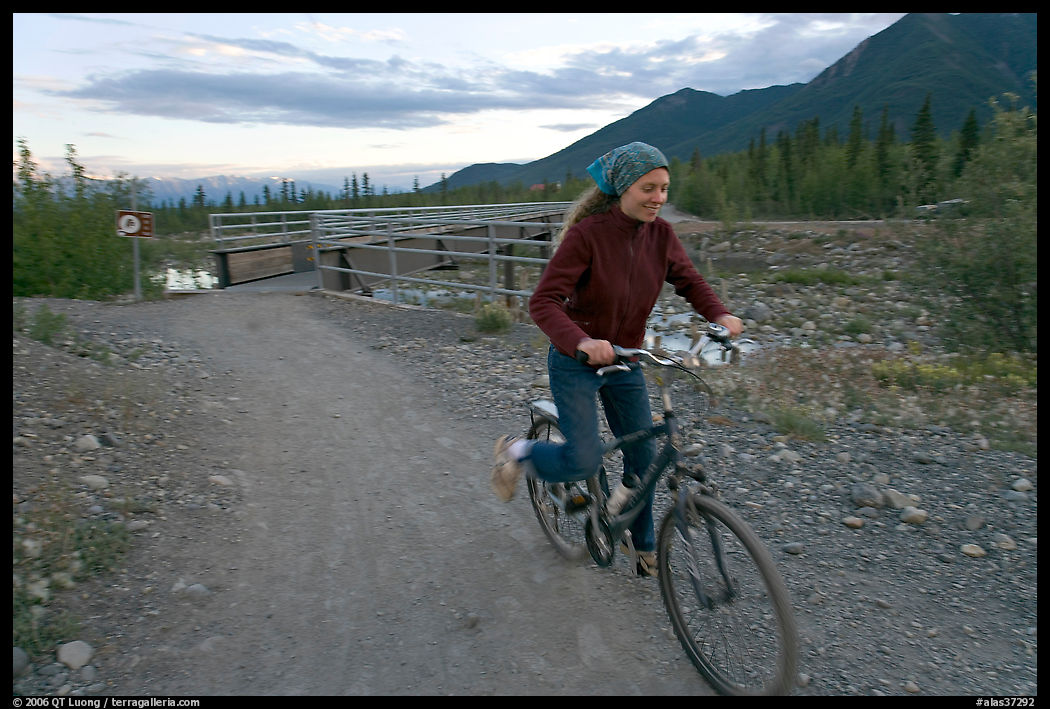 Woman on mountain bike with bridge behind. McCarthy, USA