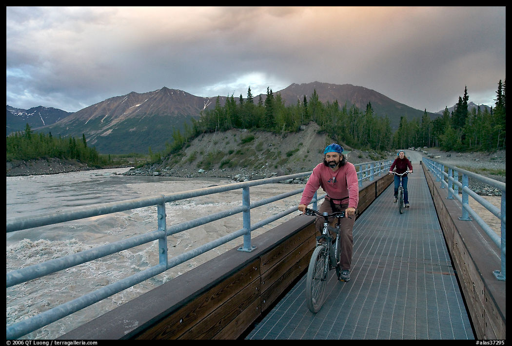 Mountain bikers crossing Kennicott River Footbridge at sunset. McCarthy, USA
