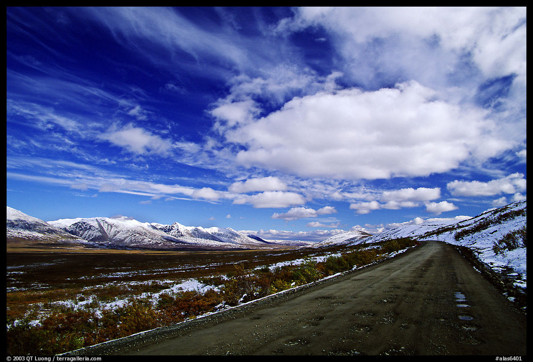 Gravel road under large white clouds. Denali Highway, Central Alaska, USA