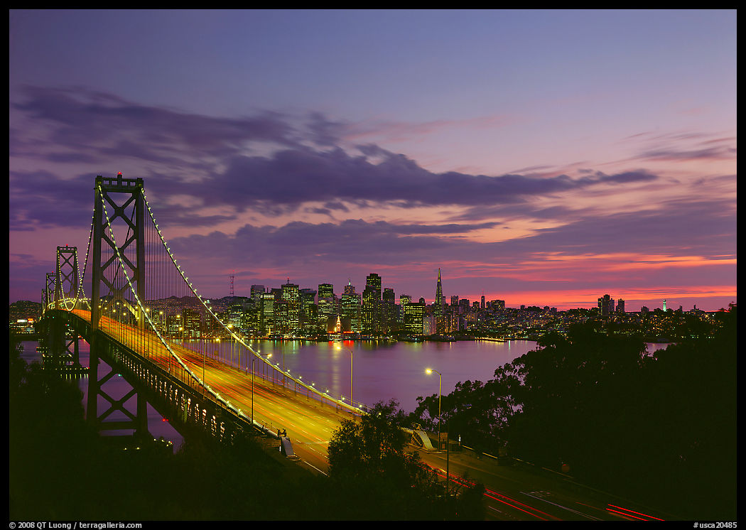 Bay Bridge and city skyline with lights at sunset. San Francisco, California, USA