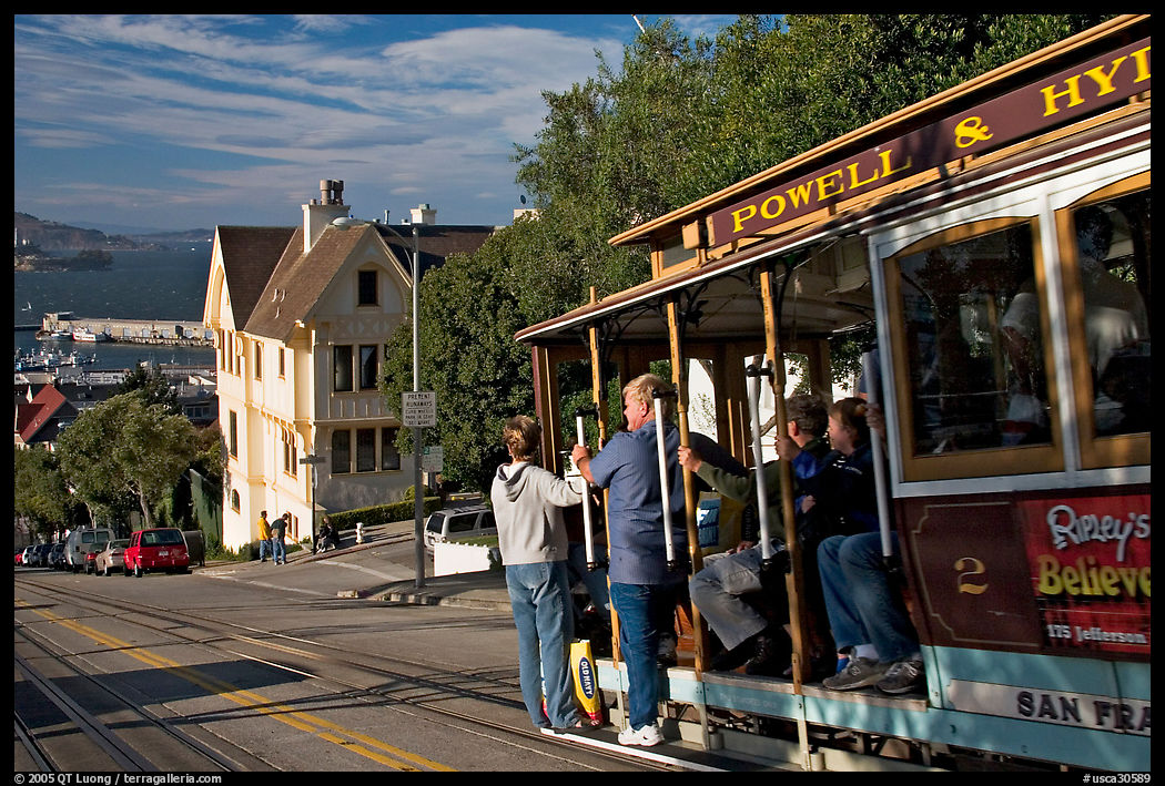 Cable car plunging with people clinging on Hyde Street, late afternoon. San Francisco, California, USA