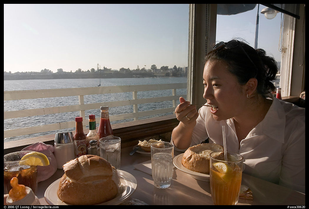 Woman eating clam chowder in a sourdough bread bowl. Santa Cruz, California, USA