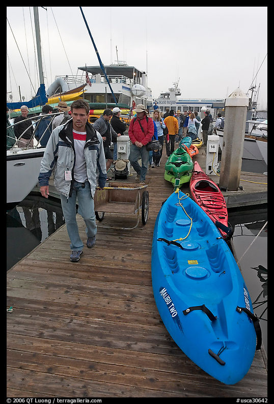 Sea kayaks and passengers awaiting loading on tour boat. California, USA