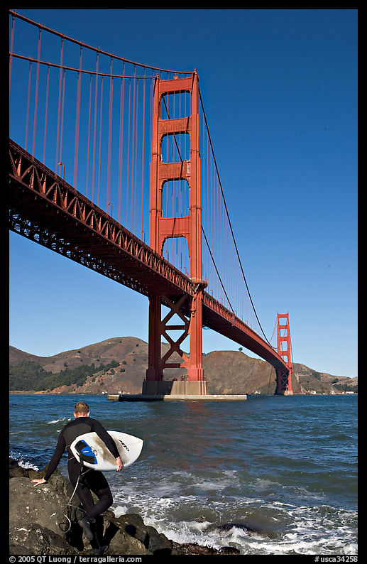 Surfer stepping on rocks and Golden Gate Bridge. San Francisco, California, USA