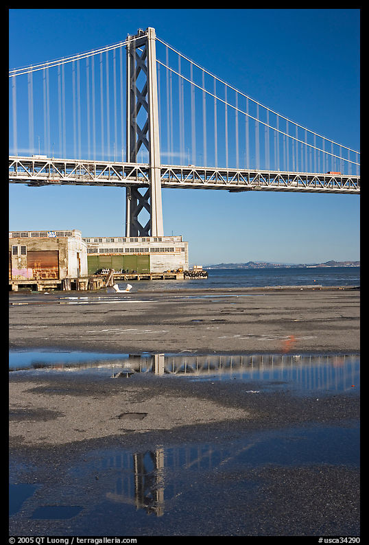 Bay Bridge reflected in water puddles. San Francisco, California, USA