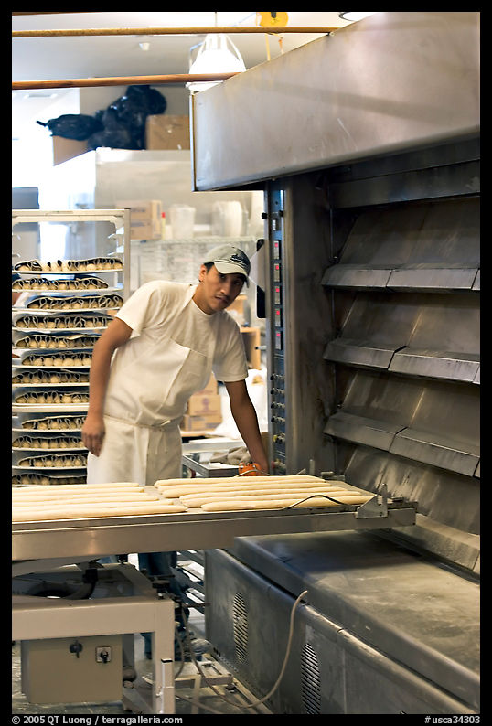 Baker loading loafs of bread into oven. San Francisco, California, USA