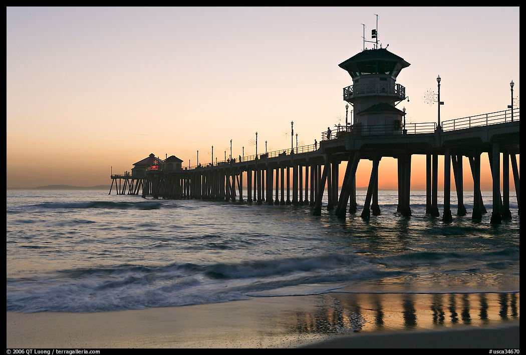The 1853 ft Huntington Pier reflected in wet sand at sunset. Huntington Beach, Orange County, California, USA