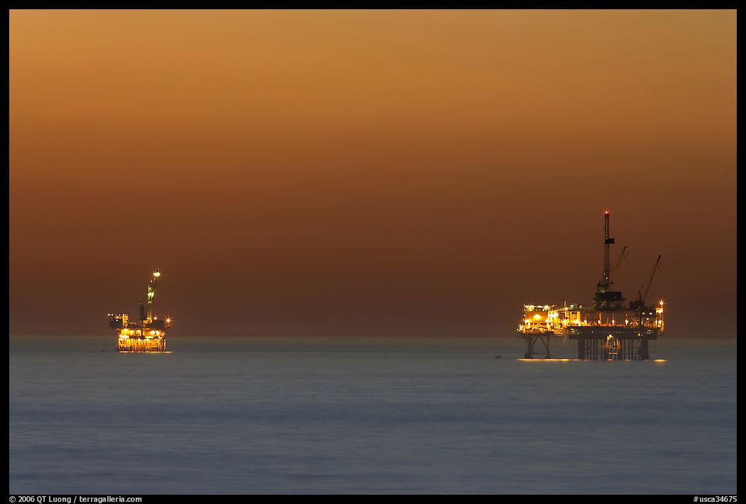 Oil drilling platforms lighted at dusk. Huntington Beach, Orange County, California, USA