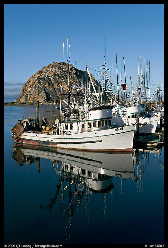 Fishing boats reflected in harbor,  and Morro Rock, early morning. Morro Bay, USA