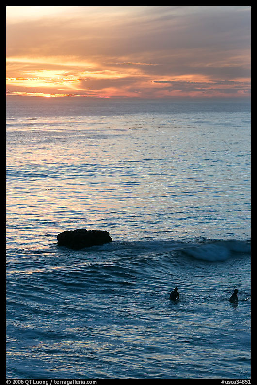 Surfers and rock at sunset. Santa Cruz, California, USA