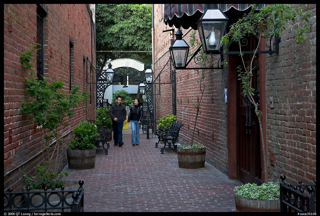 Couple walking in an alley of brick walls, San Pedro Square. San Jose, California, USA