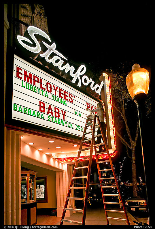 Woman on ladder arranging sign letters, Stanford Theater. Palo Alto, SF Bay area, California, USA