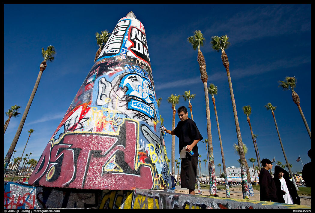 Man painting inscriptions on a graffiti-decorated tower. Venice, Los Angeles, California, USA