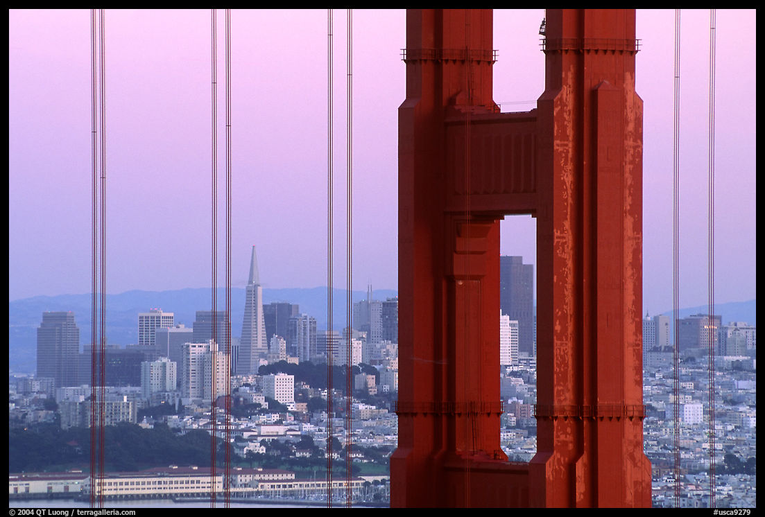 The city seen through the cables and pilars of the Golden Gate bridge, dusk. San Francisco, California, USA