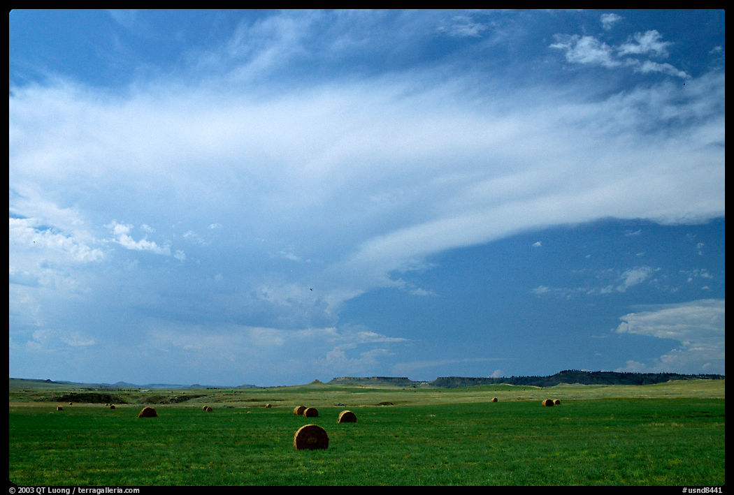 Hay rolls and storm cloud. North Dakota, USA