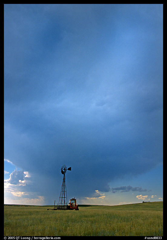 Windmill and tractor under a threatening stormy sky. North Dakota, USA