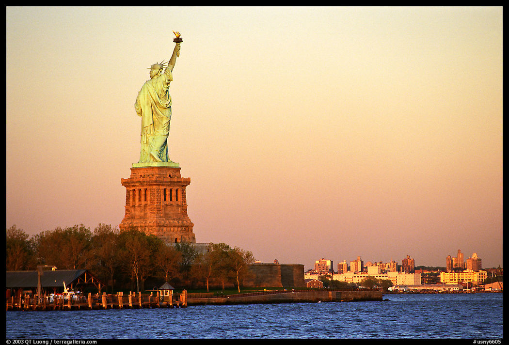 Statue of Liberty from the back Brooklyn in the background, sunset. New York City, USA