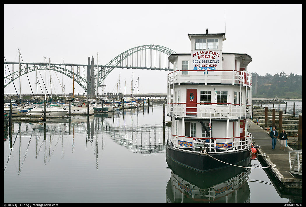 Couple walking on deck next to floating Bed and Breakfast. Newport, Oregon, USA