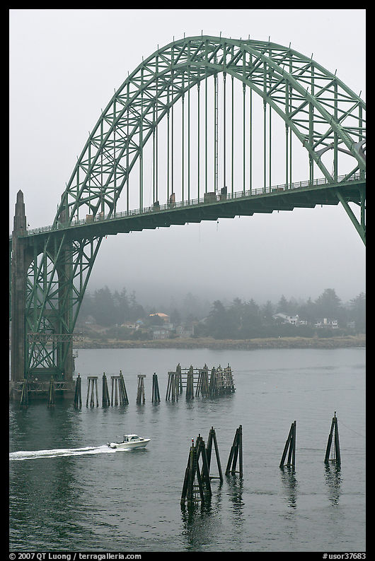 Small boat heading towards ocean under Yaquina Bay Bridge. Newport, Oregon, USA
