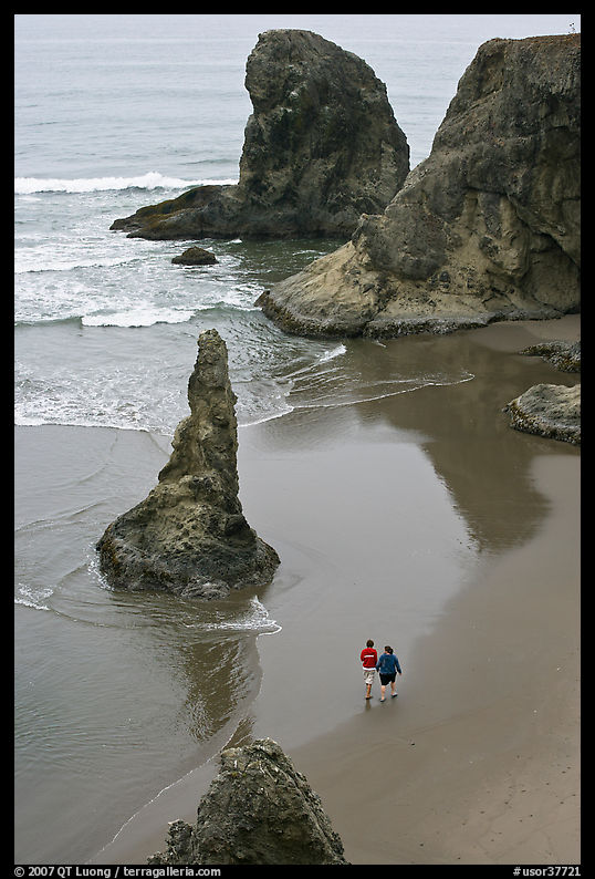 Women walking on beach among rock needles. Bandon, Oregon, USA