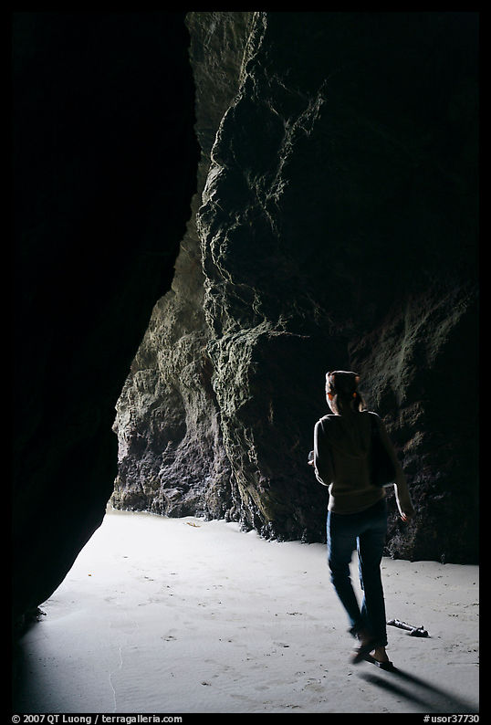 Woman walking out of sea cave. Bandon, Oregon, USA