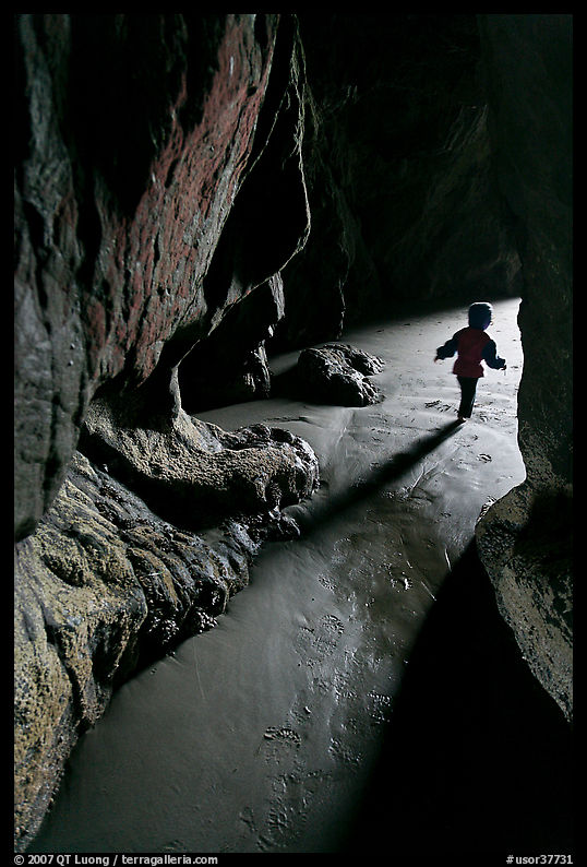 Infant walking out of sea cave. Bandon, Oregon, USA
