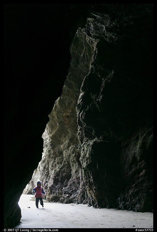 Infant walking into sea cave. Bandon, Oregon, USA
