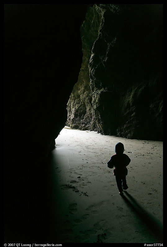 Infant walking towards the light in sea cave. Bandon, Oregon, USA