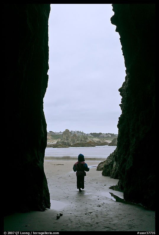 Infant standing at sea cave opening. Bandon, Oregon, USA