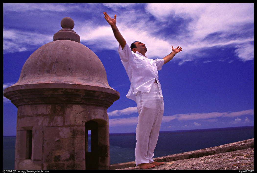 Man standing next to a lookout turret, with arms spread, El Morro Fortress. San Juan, Puerto Rico
