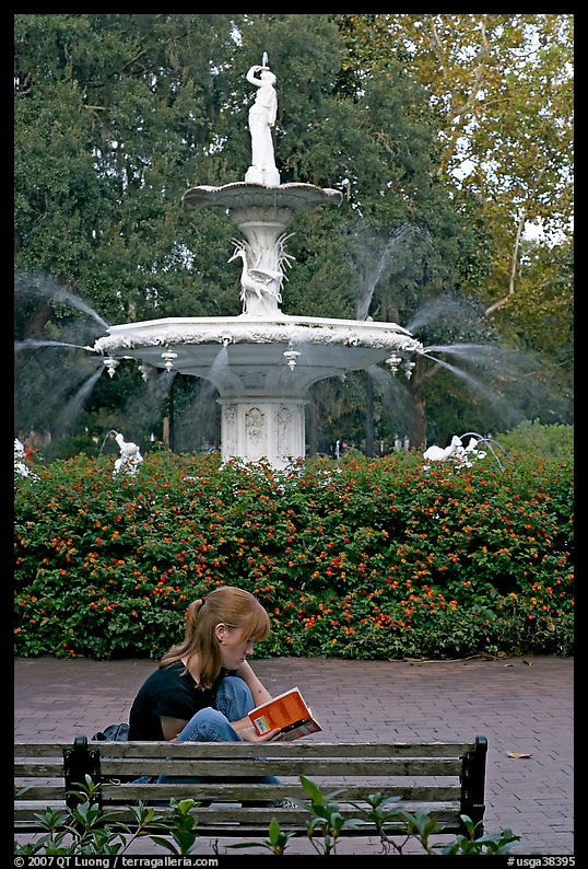 Woman sitting on bench with book in front of Forsyth Park Fountain. Savannah, Georgia, USA