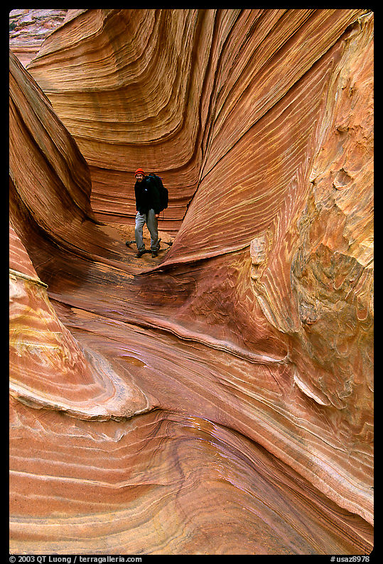 Hiker with backpack on a side formation of the Wave. Coyote Buttes, Vermilion cliffs National Monument, Arizona, USA