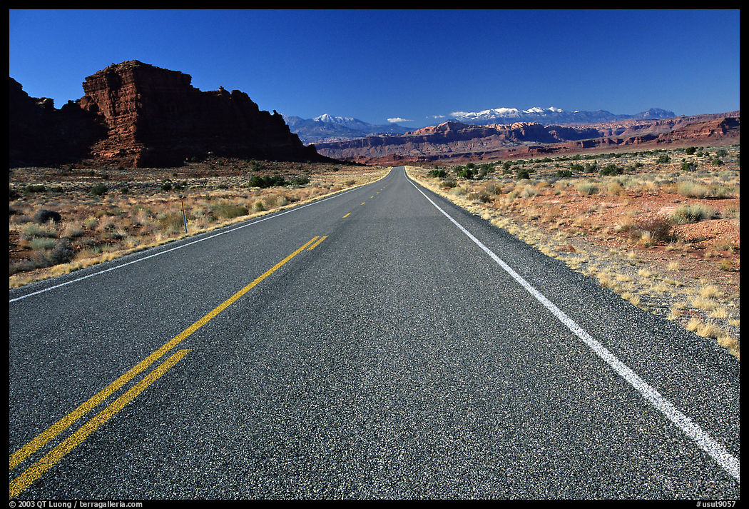 Road, sandstone cliffs, snowy mountains. Utah, USA