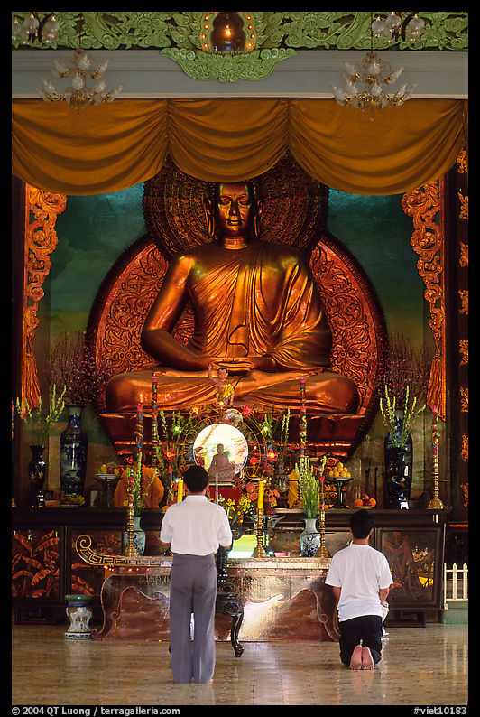 Men worshipping in front of a large Buddha state, Xa Loi pagoda. Ho Chi Minh City, Vietnam