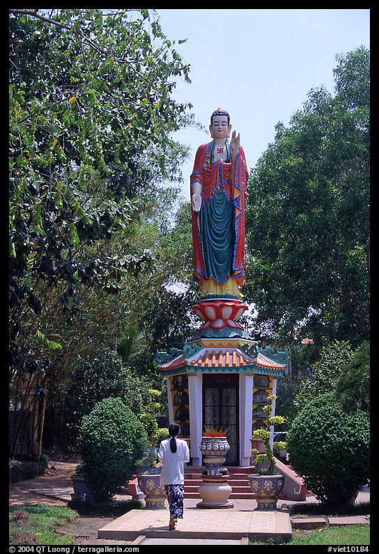 Woman praying under a large buddhist statue. Ho Chi Minh City, Vietnam