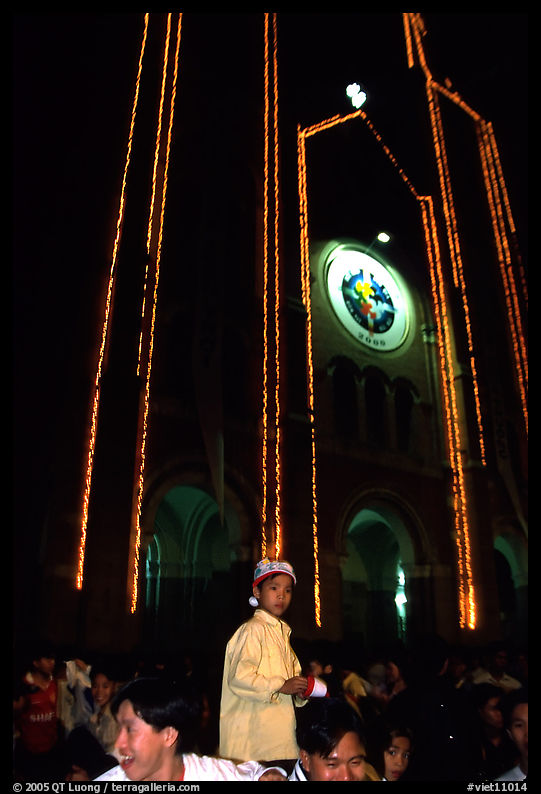 Child with christmas hat in front of St Joseph Cathedral on Christmas eve. Ho Chi Minh City, Vietnam