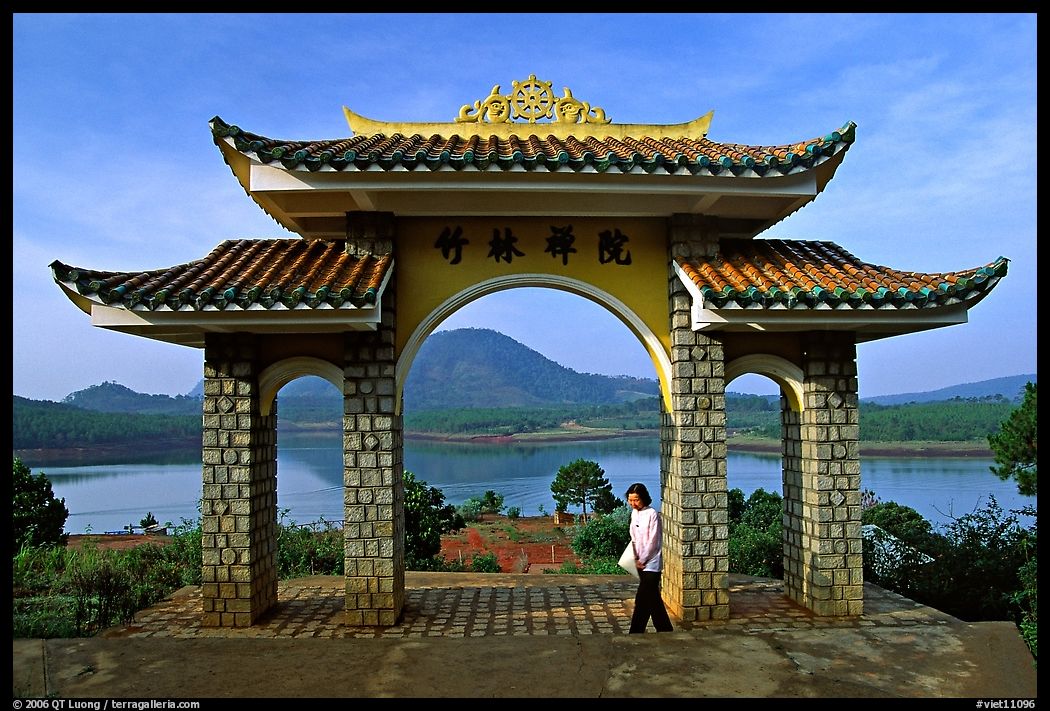 Pagoda gate with woman standing near lake. Da Lat, Vietnam