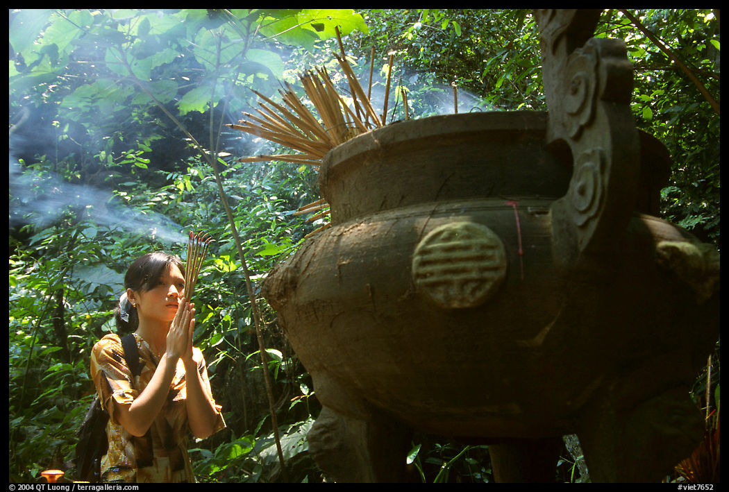 Visitor praying at an urn with incense near the entrance of Phong Nha Cave. Vietnam