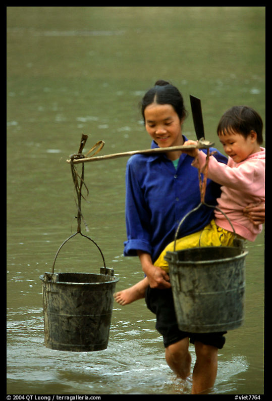 Woman of the Tay minority carrying crossing the river with child, Ba Be Lake. Vietnam
